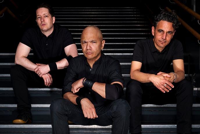The band Danko Jones, three members in black attire staring intently against a gray backdrop.