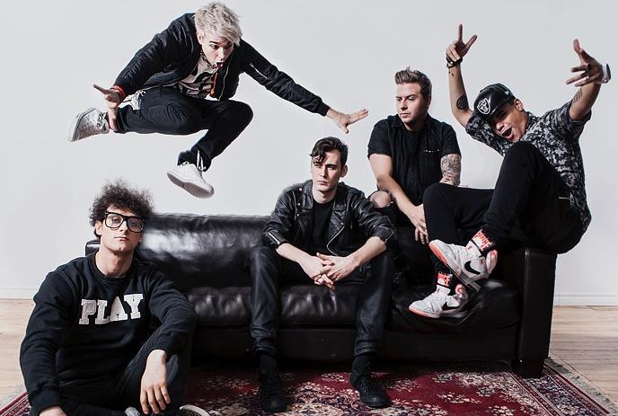 The band Down With Webster posing dynamically with jumps and sits around a black couch on a red rug.