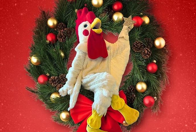 Holiday wreath with red bow and ornaments frames plush chicken figure under a red background.