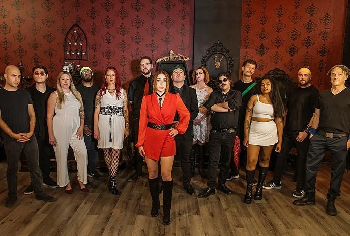 Colorful band poses in brick archway with instruments; vibrant outfits suggest artistic, musical energy.