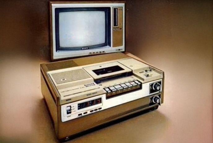 Vintage TV and VCR setup with tactile buttons and dials under a dark brown background.