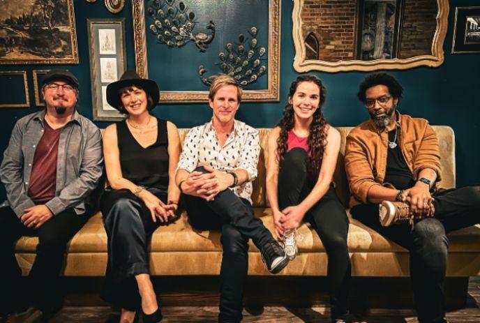 5 members of  Classic Troubadours sitting on a couch together in a fancy room, posing for the camera.