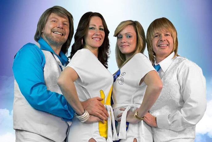 Two couples standing together with a blue light in the background.