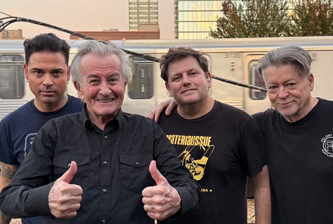 4 members of the band FEAR, posing in front of a train during a sunset.