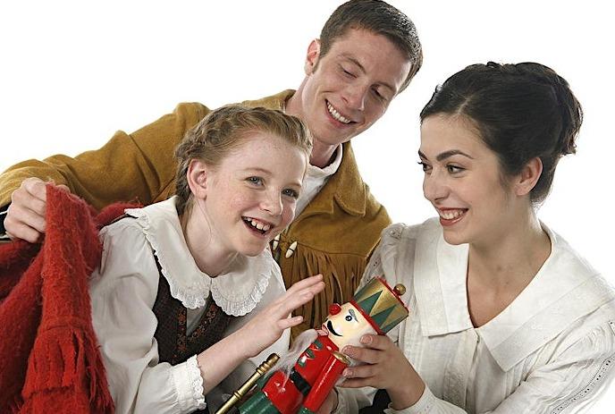 Two adults giving a child a gift of a red nutcracker doll.