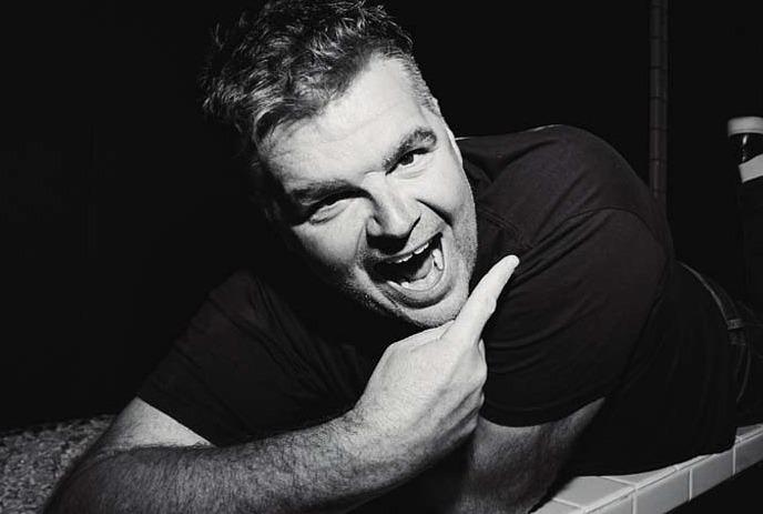 A black and white photo of Ian Bagg, posing for the camera, smiling.