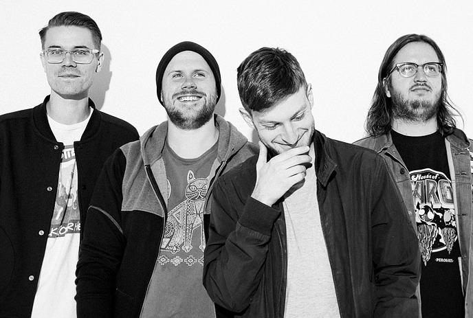 A black and white photo of the 4 band members of Pup, standing against a white background, posing for the camera.