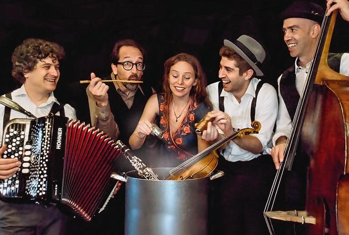 The band Schmaltz & Pepper happily stirring instruments like accordion, clarinet, violin, and bass into a big pot.