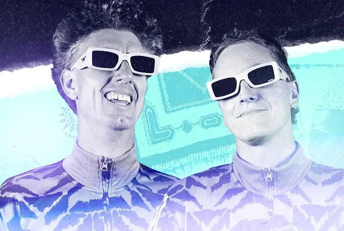 2 band members of Skiitour wearing glasses and posing for the camera in front of a turquoise background.