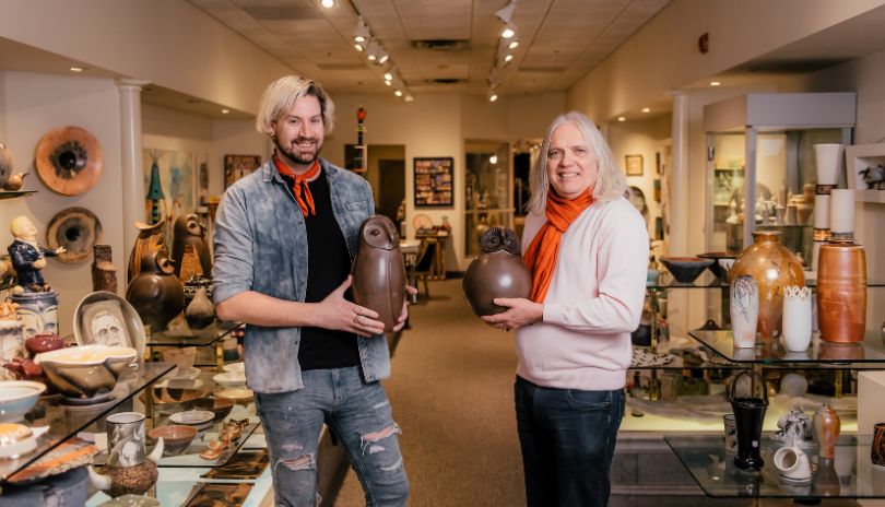 A women holding a polaroid photograph of the owners of Jonathon Bancroft-Snell Gallery in front of their storefront.