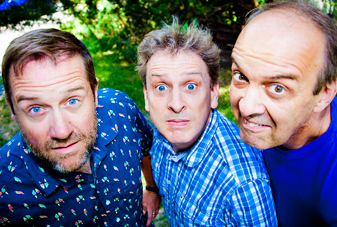 The 3 band members of The Arrogant Worms, making funny faces at the camera while posing outside on a sunny day.