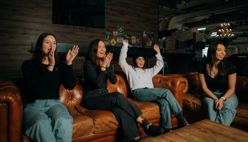 A group of people cheer on a couch at The Club House.
